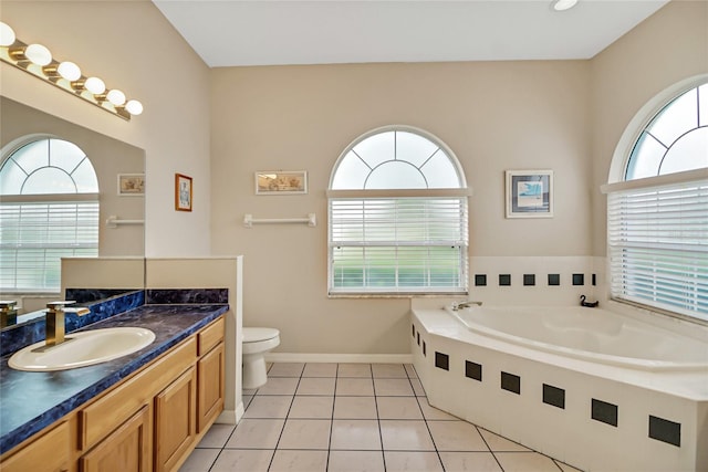 bathroom with tile patterned flooring, vanity, tiled bath, and toilet