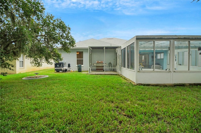 rear view of house featuring a sunroom, a yard, and an outdoor fire pit