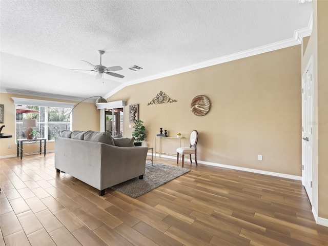 living room with wood-type flooring, vaulted ceiling, a textured ceiling, ornamental molding, and ceiling fan