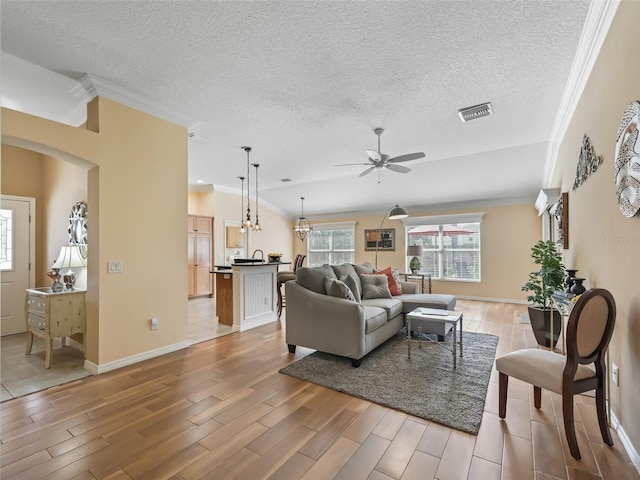 living room featuring ceiling fan, crown molding, a textured ceiling, and light hardwood / wood-style flooring