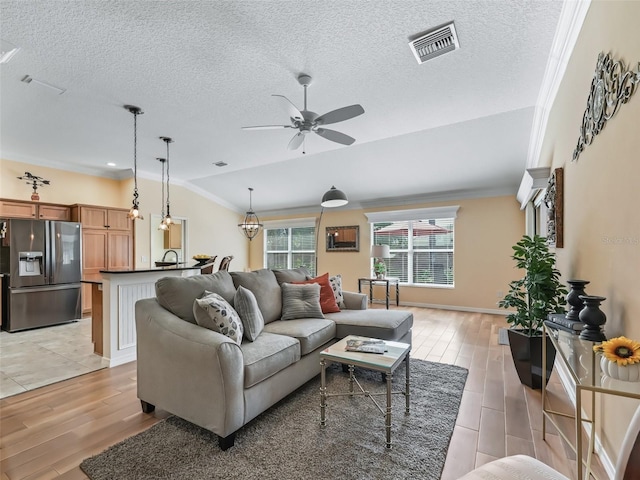 living room with ornamental molding, lofted ceiling, and light wood-type flooring