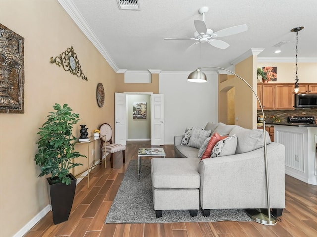 living room featuring crown molding, ceiling fan, and a textured ceiling