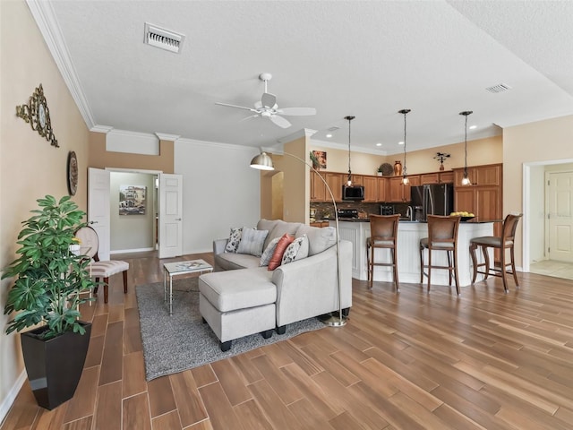 living room with ornamental molding, hardwood / wood-style floors, a textured ceiling, and ceiling fan