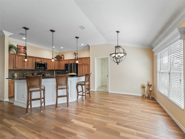 kitchen with tasteful backsplash, black fridge, a breakfast bar area, and pendant lighting