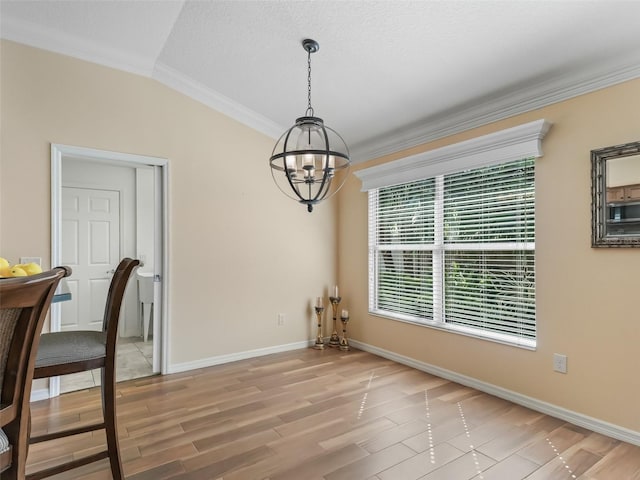 unfurnished dining area featuring crown molding, a chandelier, vaulted ceiling, and light hardwood / wood-style flooring