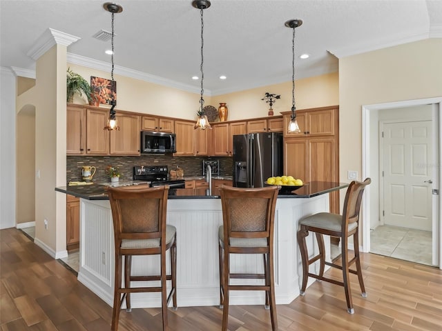 kitchen featuring an island with sink, pendant lighting, refrigerator with ice dispenser, and black range with electric cooktop