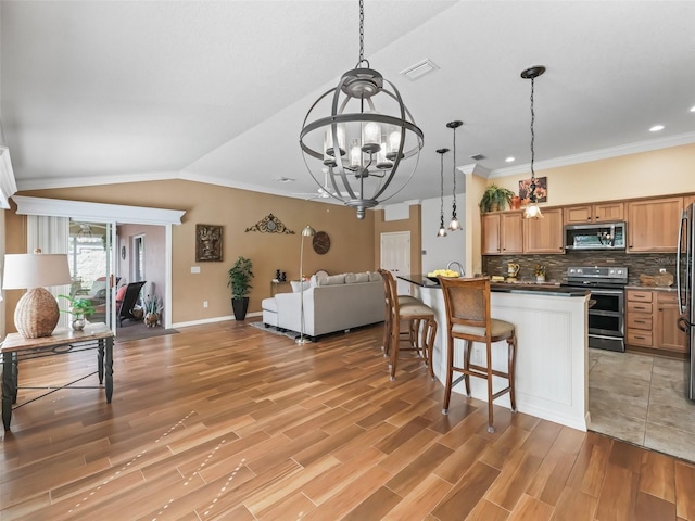 kitchen featuring lofted ceiling, tasteful backsplash, decorative light fixtures, a notable chandelier, and stainless steel appliances