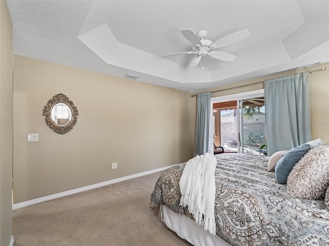 carpeted bedroom with access to exterior, ceiling fan, and a tray ceiling