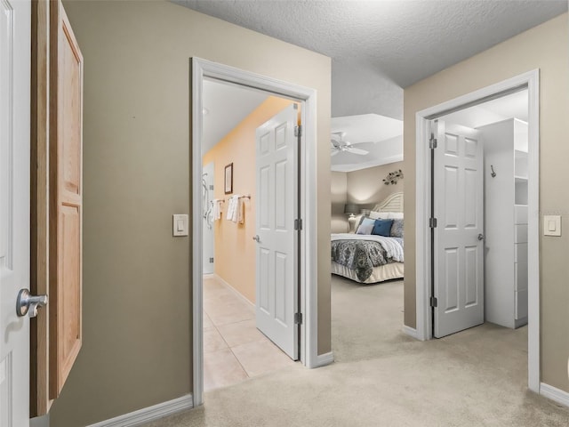 hallway featuring light colored carpet and a textured ceiling