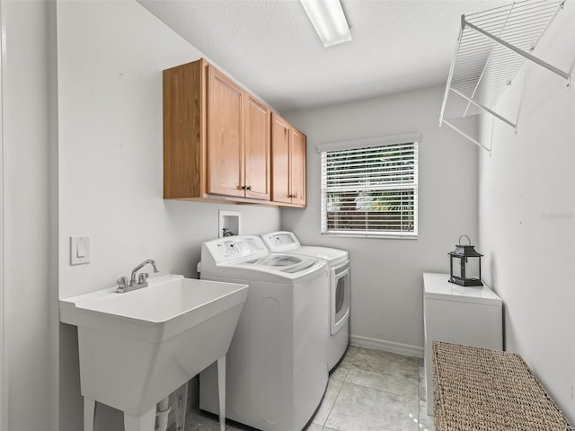 clothes washing area featuring sink, cabinets, a textured ceiling, light tile patterned floors, and washing machine and dryer