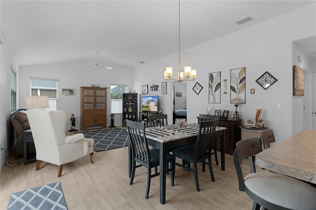 dining space with lofted ceiling, ceiling fan with notable chandelier, light hardwood / wood-style flooring, and plenty of natural light