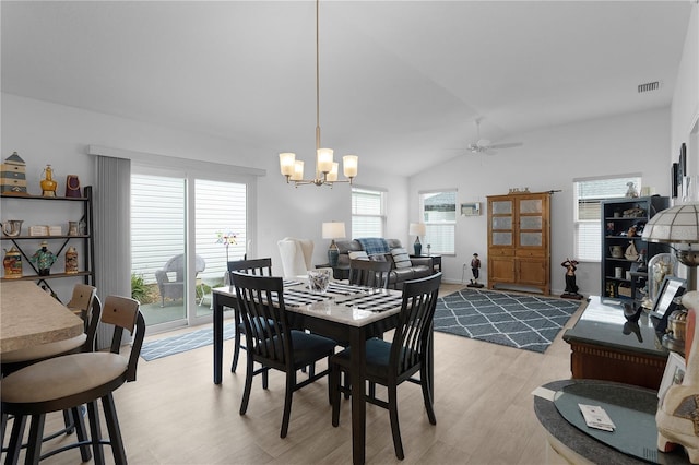 dining area featuring lofted ceiling, ceiling fan with notable chandelier, and light hardwood / wood-style flooring