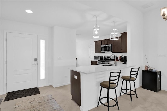 1392 Kenneth St, The Villages, FL 34762 - kitchen featuring a breakfast bar, sink, dark brown cabinets, appliances with stainless steel finishes, and kitchen peninsula