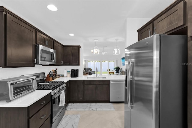 1392 Kenneth St, The Villages, FL 34762 - kitchen featuring pendant lighting, dark brown cabinetry, stainless steel appliances, and sink