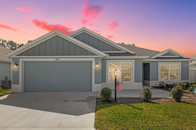 view of front of home featuring a garage, a yard, and central air condition unit