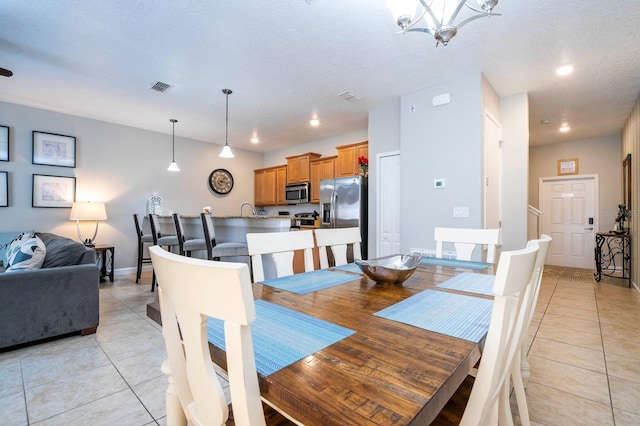 tiled dining space with sink, a notable chandelier, and a textured ceiling