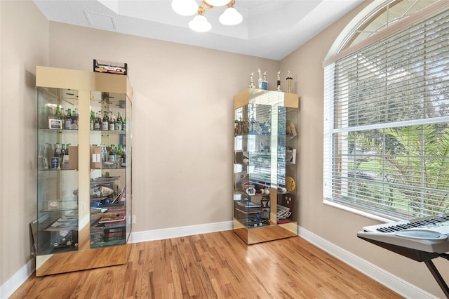 unfurnished dining area with wood-type flooring, a notable chandelier, and a tray ceiling