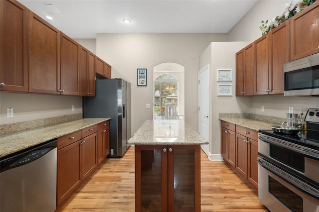 kitchen with a center island, light stone countertops, light hardwood / wood-style floors, and appliances with stainless steel finishes