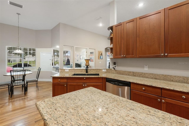 kitchen with sink, light stone counters, light wood-type flooring, stainless steel dishwasher, and pendant lighting