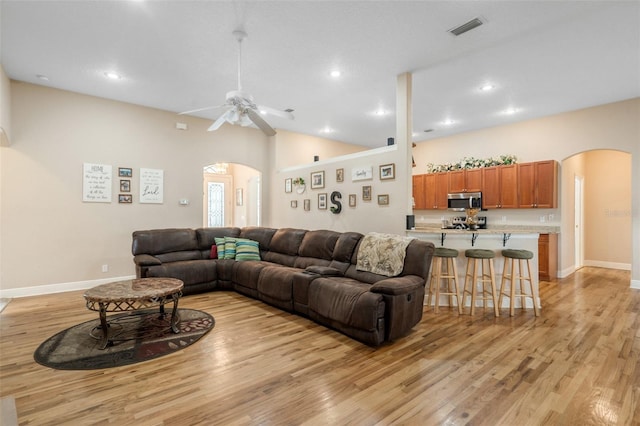 living room with ceiling fan, lofted ceiling, and light hardwood / wood-style floors