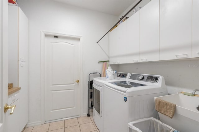 clothes washing area with cabinets, sink, light tile patterned floors, and independent washer and dryer