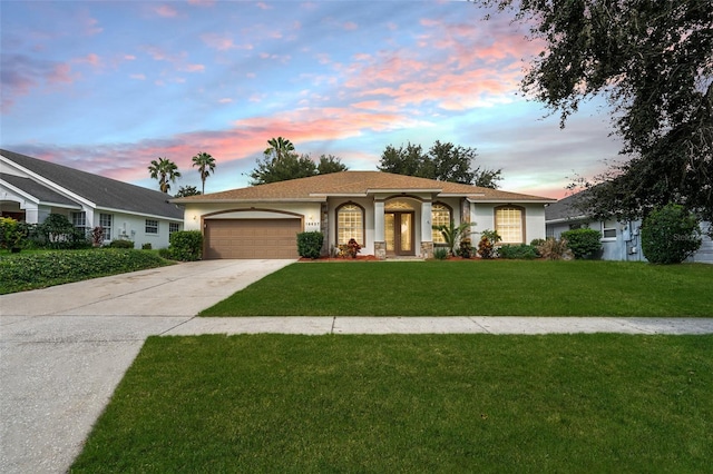 ranch-style home with a garage and a lawn