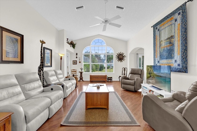 living room with hardwood / wood-style flooring, ceiling fan, high vaulted ceiling, and a textured ceiling