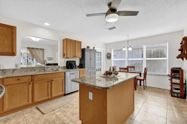 kitchen featuring a kitchen island, decorative light fixtures, dishwasher, sink, and light stone counters