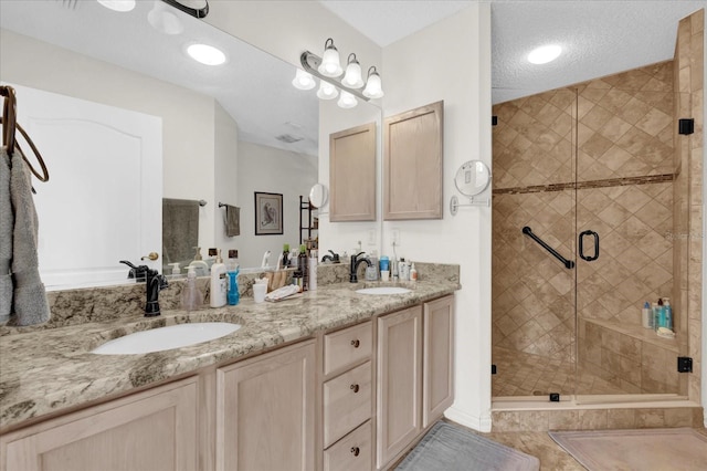 bathroom with vanity, a shower with door, and a textured ceiling