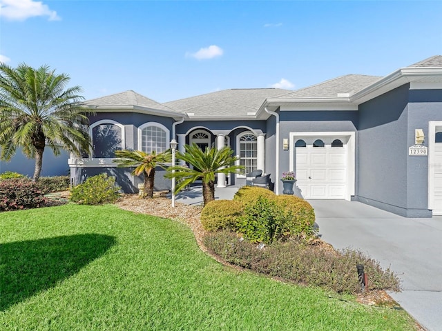 ranch-style home featuring a garage, driveway, a front yard, and stucco siding