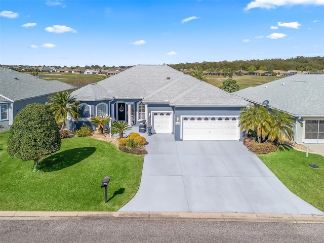 view of front of house featuring a shingled roof, concrete driveway, an attached garage, a front yard, and a residential view