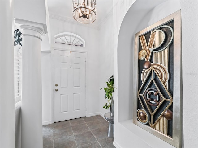 entrance foyer featuring arched walkways, ornate columns, an inviting chandelier, ornamental molding, and baseboards