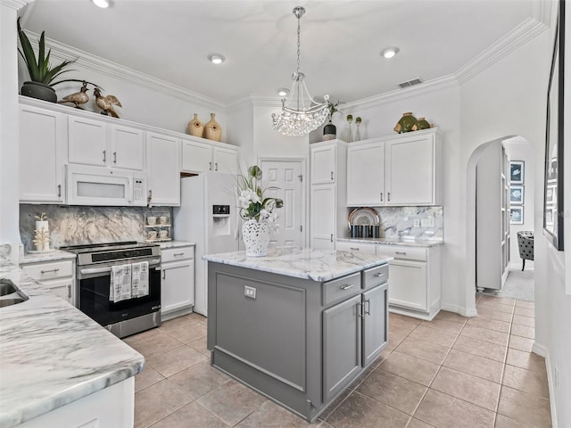 kitchen with white appliances, visible vents, arched walkways, a kitchen island, and white cabinetry