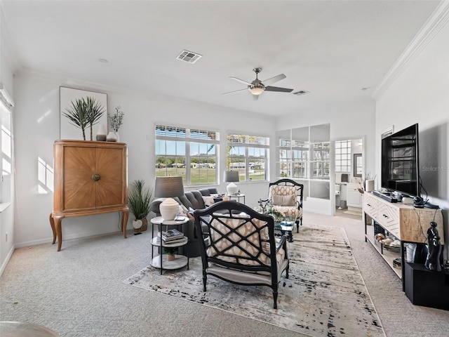 living area featuring ornamental molding, light colored carpet, visible vents, and a ceiling fan