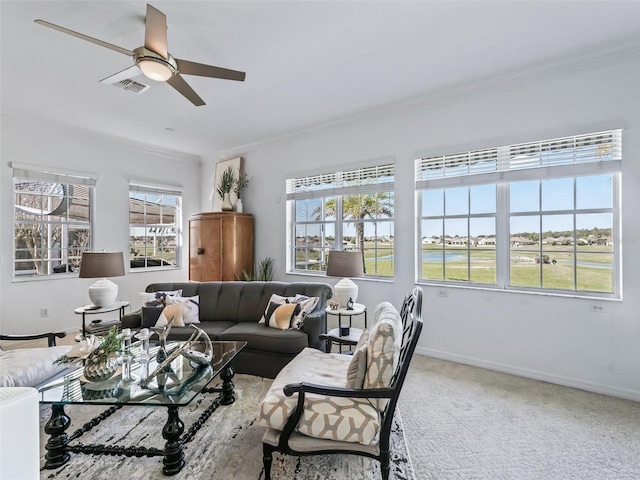 carpeted living area with baseboards, a ceiling fan, visible vents, and crown molding