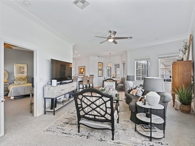 living area featuring ceiling fan, ornamental molding, visible vents, and light colored carpet