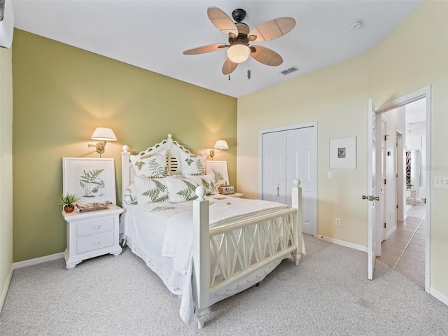 bedroom featuring ceiling fan, light colored carpet, visible vents, baseboards, and a closet