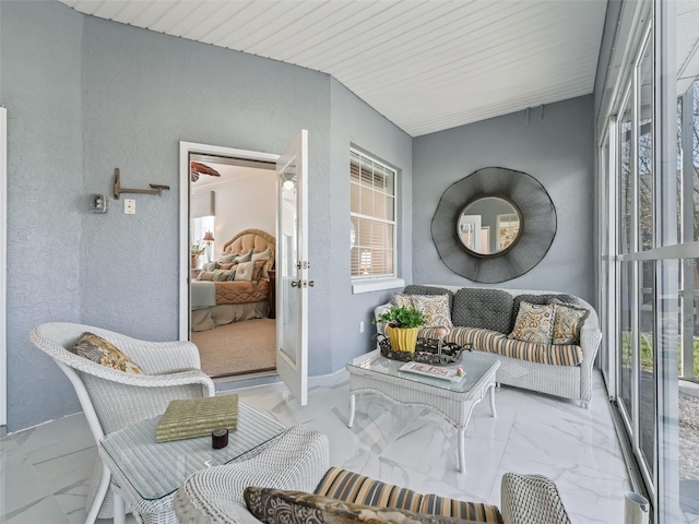 sitting room featuring marble finish floor and a textured wall