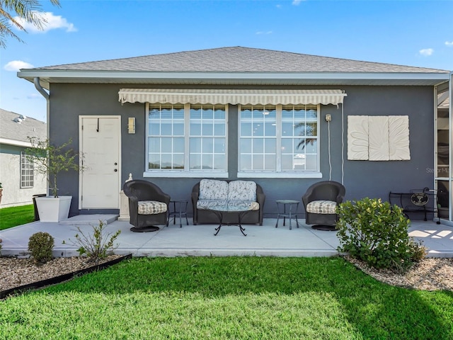 rear view of house with a yard, a patio, a shingled roof, and stucco siding