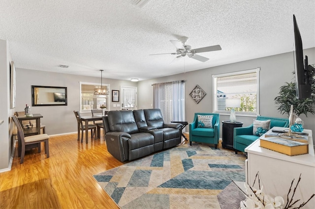 living room featuring hardwood / wood-style flooring, ceiling fan, and a textured ceiling