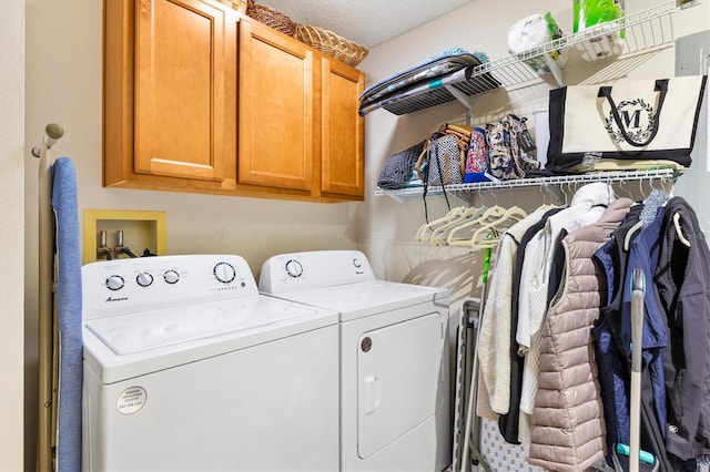 washroom featuring cabinets, washing machine and clothes dryer, and a textured ceiling