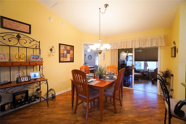 dining space with dark wood-type flooring, a chandelier, and vaulted ceiling