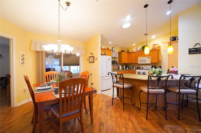 dining room featuring vaulted ceiling, a chandelier, and light wood-type flooring