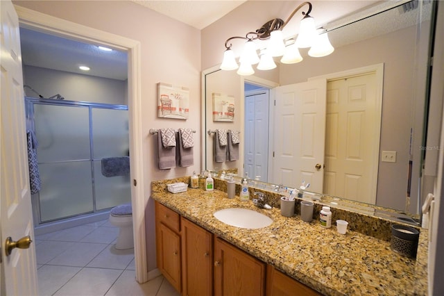 bathroom featuring tile patterned floors, toilet, a shower with shower door, and vanity