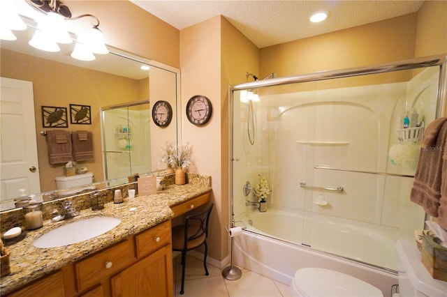 full bathroom featuring combined bath / shower with glass door, vanity, a textured ceiling, tile patterned floors, and toilet