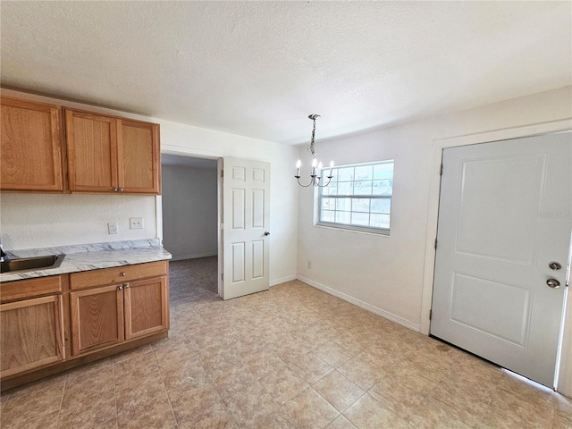 kitchen featuring sink, a textured ceiling, a chandelier, and decorative light fixtures