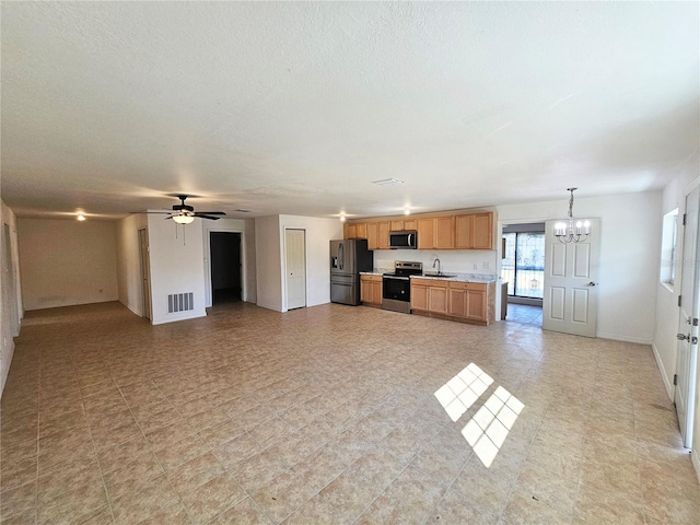 kitchen with sink, a textured ceiling, appliances with stainless steel finishes, pendant lighting, and ceiling fan with notable chandelier