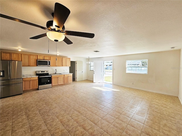 kitchen with sink, a textured ceiling, ceiling fan, and appliances with stainless steel finishes