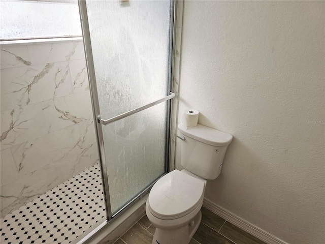 bathroom featuring toilet and a shower with shower door