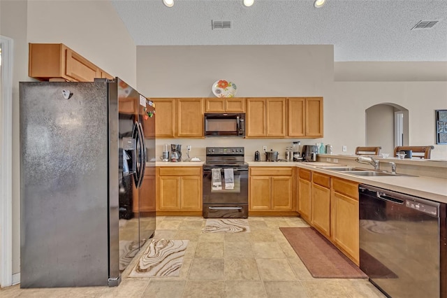 4078 Waltham Forest Dr, Tavares, FL 32778 - kitchen with light brown cabinetry, sink, black appliances, and a textured ceiling